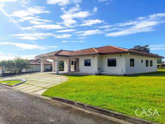 Front view of single-story Mediterranean house with red tile roof and manicured yard Boquete Panama