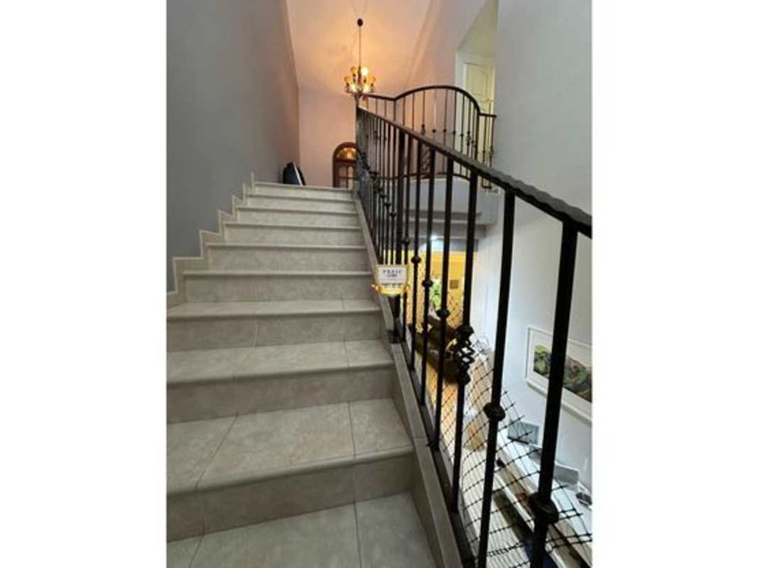Interior staircase with iron railing and chandelier at Palmeras del Este Panama luxury home