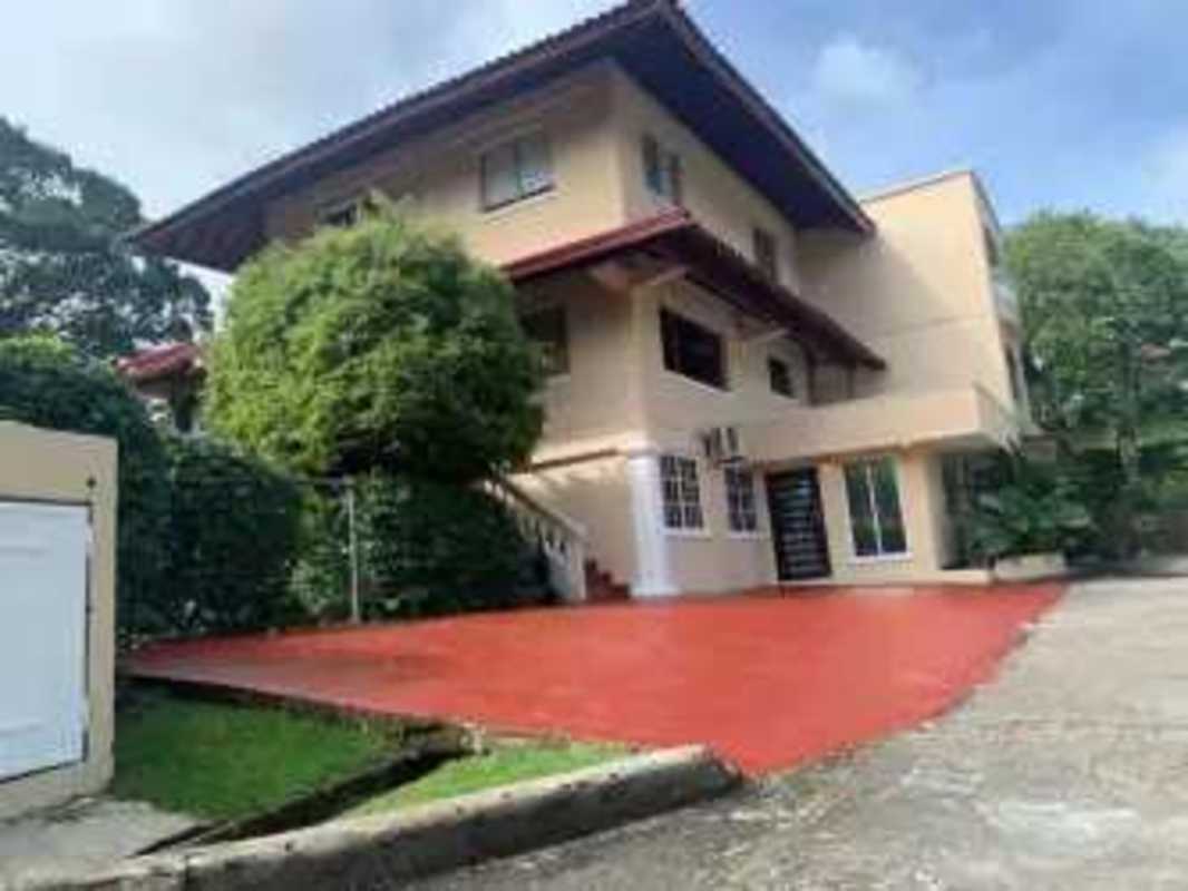 Beige multi-story house with red roof, driveway and garden in Albrook Panama