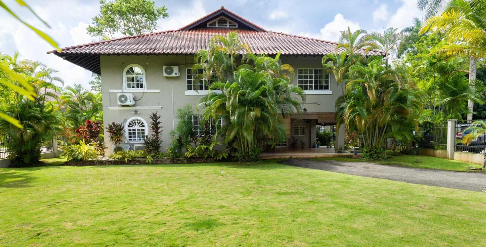 Two-story luxury house with red tile roof and tropical garden in Albrook Panama