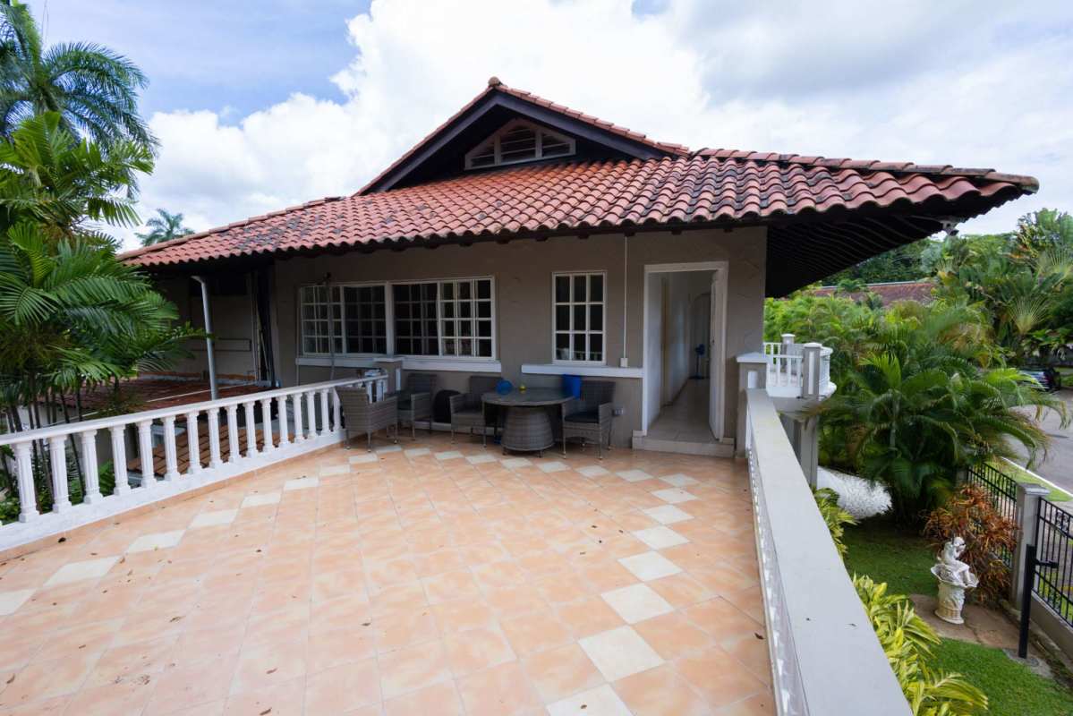 Spacious tiled outdoor terrace surrounded by lush landscaping in Albrook house
