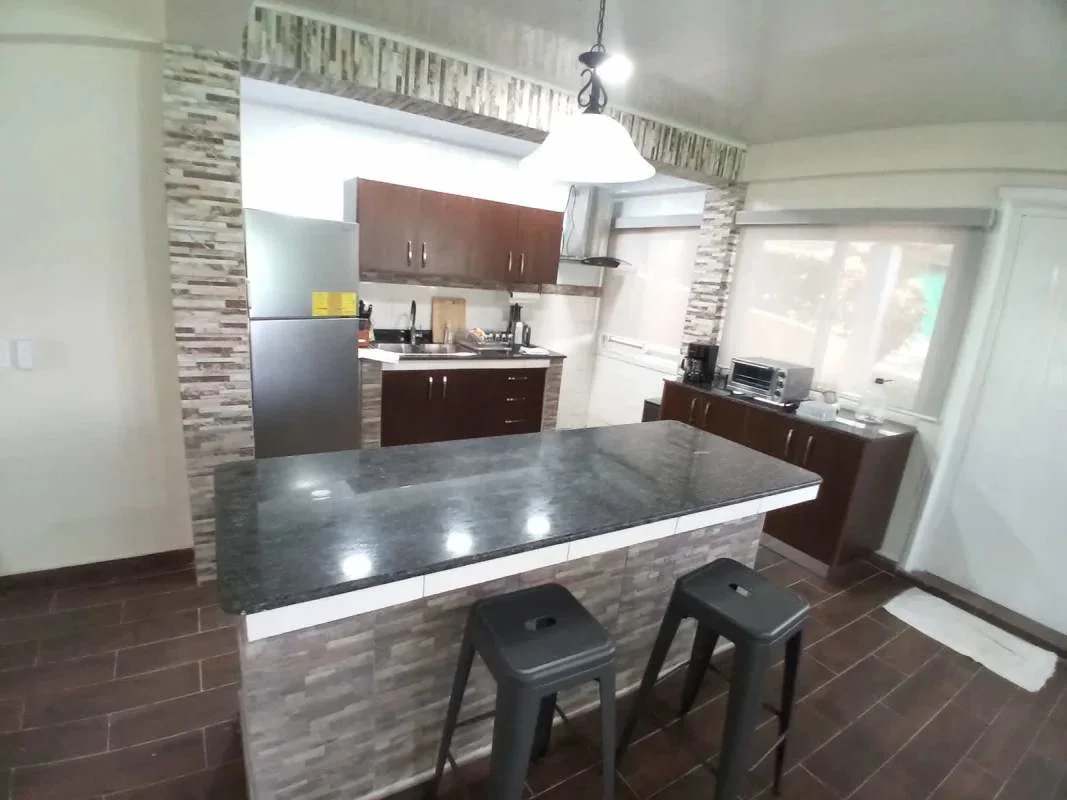 Modern kitchen with granite island, pendant lighting and wood cabinetry in Los Rios Panama