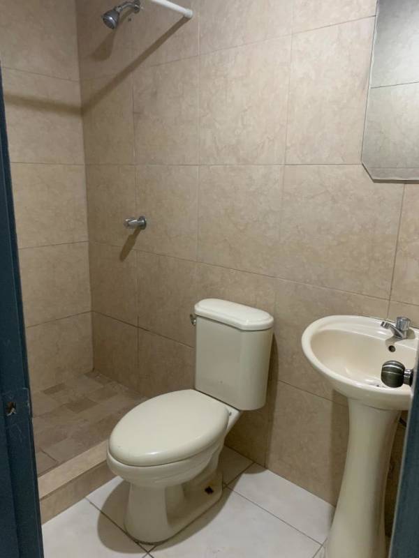 Simple bathroom with beige tiles, pedestal sink, shower Mateo Iturralde San Miguelito Panama
