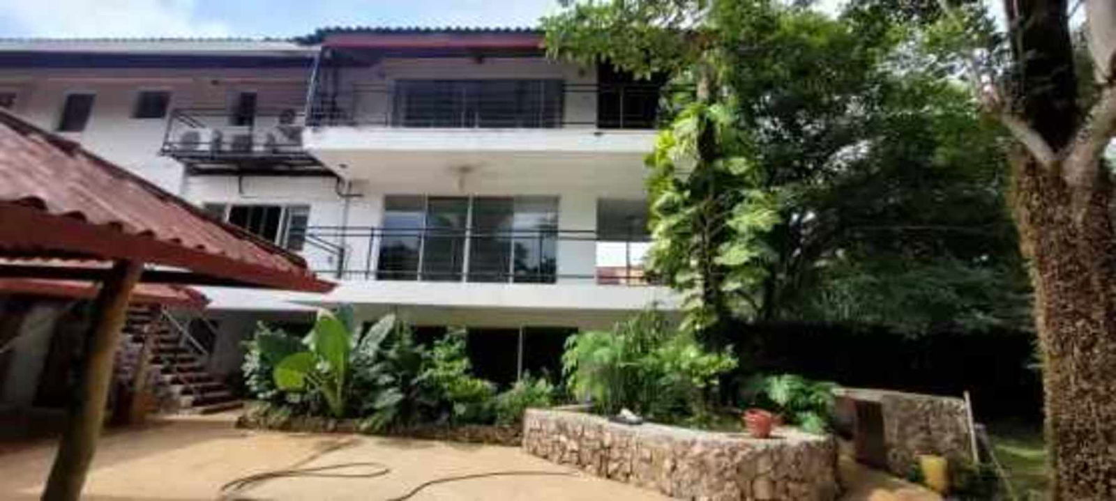 Large patio with red tiles, wooden roof beams, hammock and garden view in Albrook house Panama