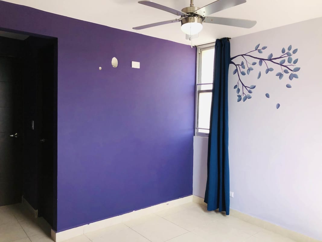 Bedroom with purple accent wall, large window and ceiling fan in PH Villa Zaita Panama