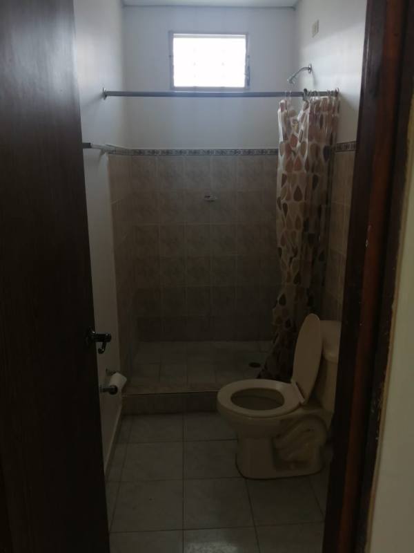 Small bathroom with curtain shower, frosted glass window, toilet in Colinas del Sol Panama
