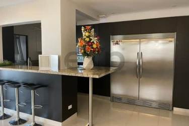 Kitchen with marble countertops, stainless refrigerator, breakfast bar and floral decor in Woodlands Panama Pacifico home