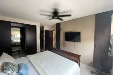 Bedroom with mounted TV, ceiling fan, dark wood sliding closet doors in Panama Pacifico property