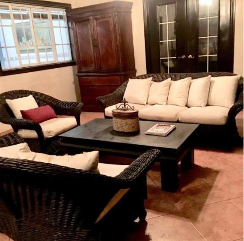 Living room with wicker furniture, cream cushions, tile floors in Costa Bay Panama City