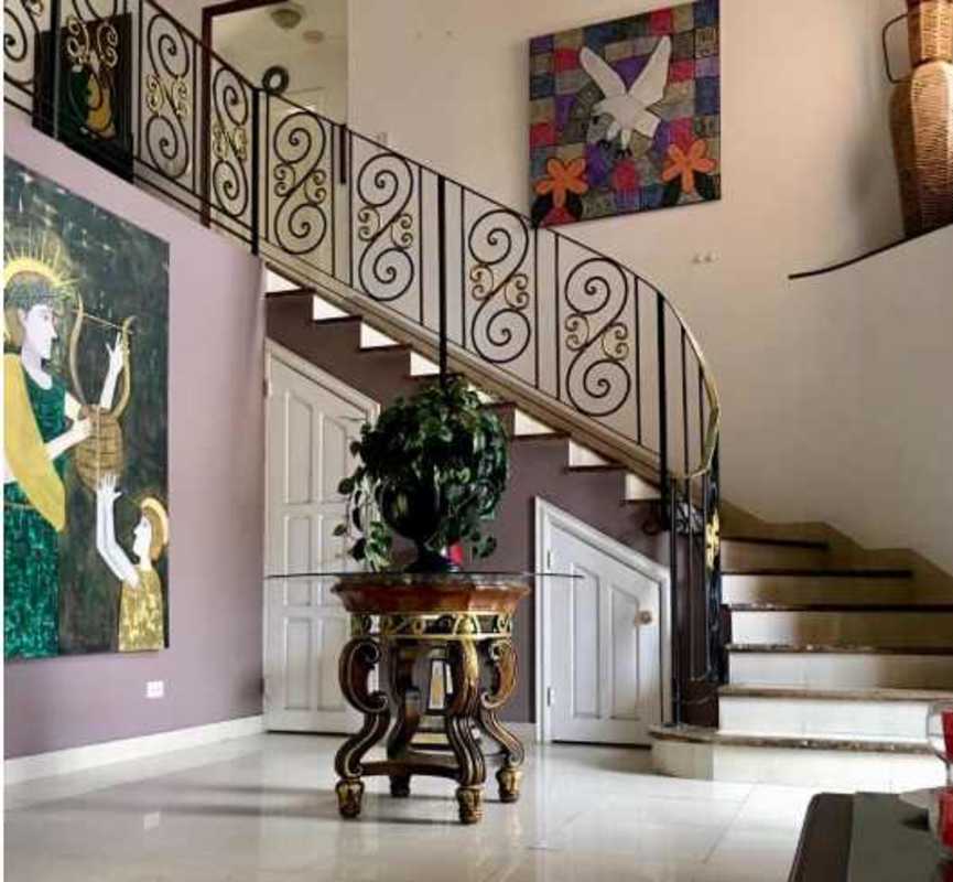Elegant foyer entrance with curved staircase and iron railing, decorative art in Costa Bay Panama