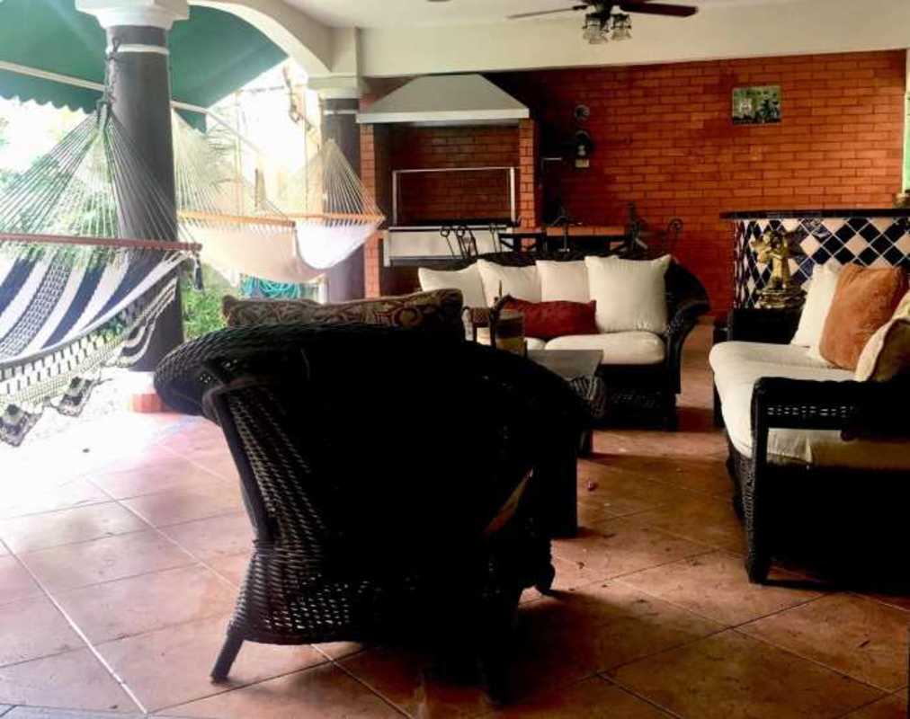 Covered outdoor patio with hammock, brick wall, barbecue area, tropical garden in Costa Bay Costa del Este Panama City