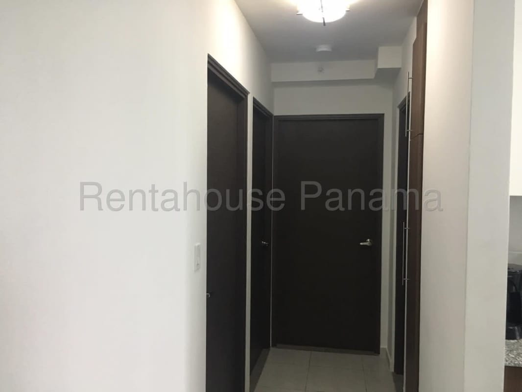 Minimalist apartment hallway with dark doors and tile floors in PH Trinity Panama City