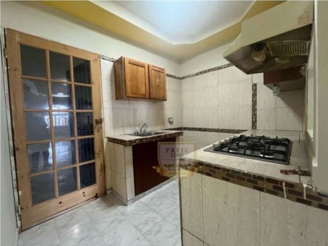 Kitchen with wooden cabinets, tile backsplash, gas stove and glass door in Tocumen house for sale