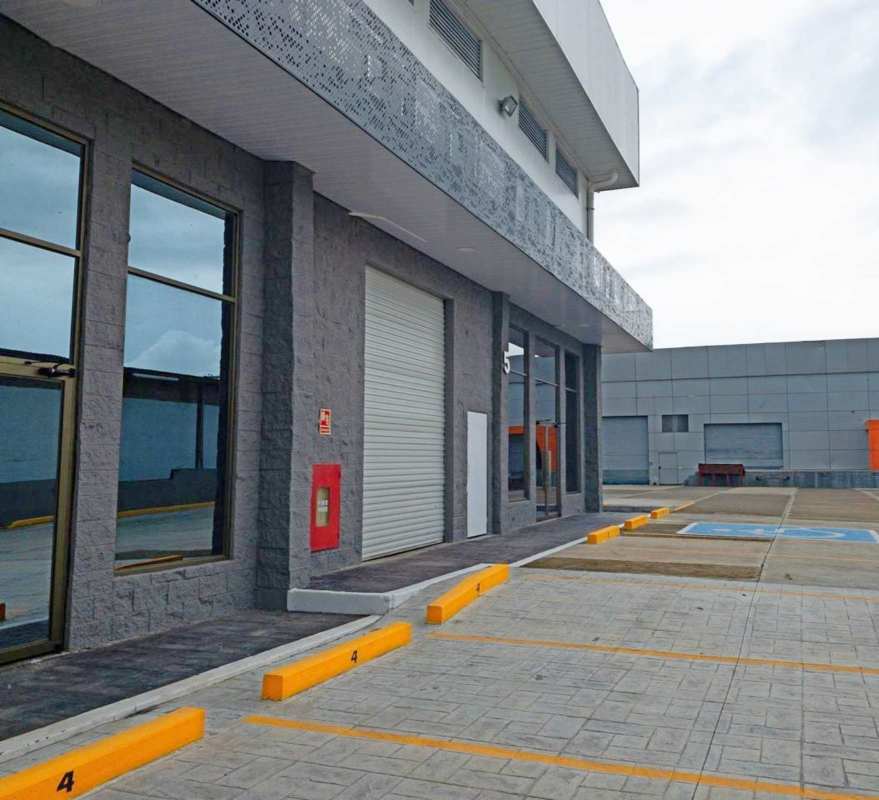 Modern facade with large glass windows, rolling door and parking at Via Tocumen warehouse rental Panama