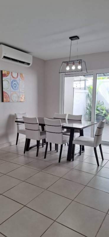 Dining room with six white chairs around dark table, glass door to outdoor patio, inside PH Victoria