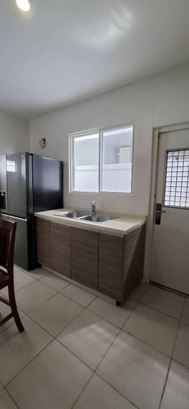 Modern kitchen with double sink, large window, refrigerator inside PH Victoria house Panama