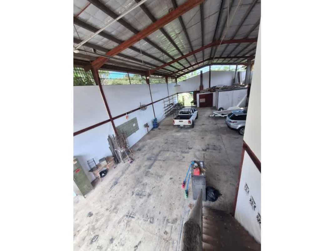 Warehouse with high metal roof, open parking for vehicles and industrial shelving in Panama City