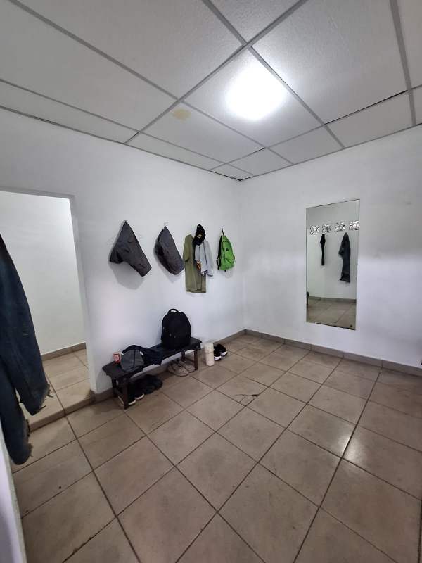 Simple changing room with bench mirror tiled floor and hanging hooks industrial warehouse Las Acacias