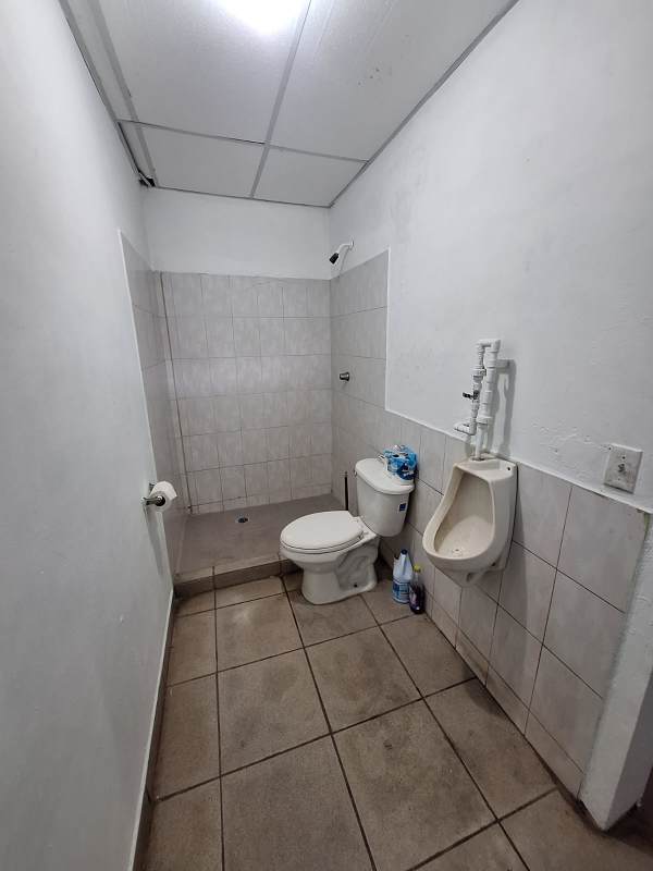 Utilitarian bathroom with toilet, urinal, shower in commercial warehouse Las Acacias Panama City