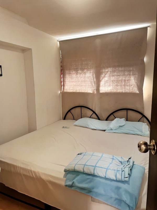 Minimalist bedroom with large bed, pillows, curtain-covered window at PH Plaza Bella Vista Panama