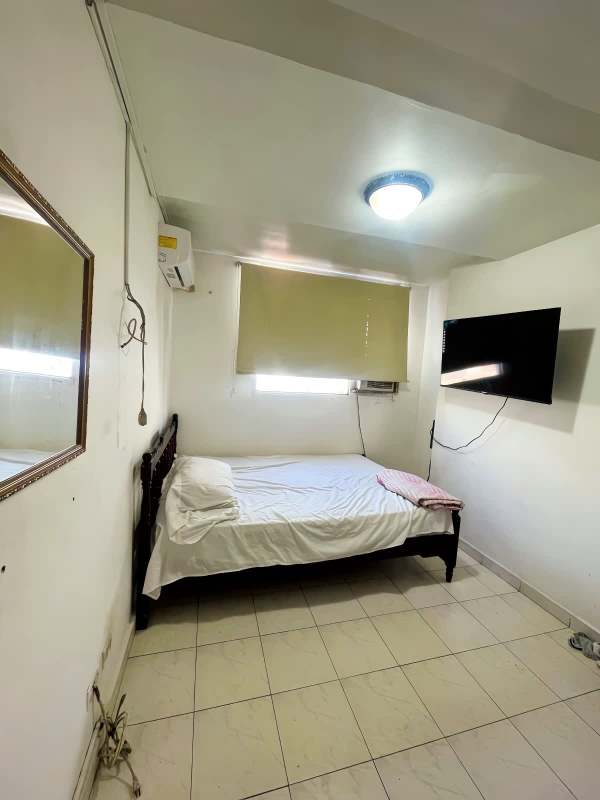 Minimalist furnished bedroom with bed, AC, TV, mirror and blinds at Plaza Bella Vista La Cresta
