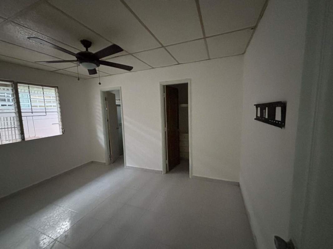 Bright bedroom with AC ceiling fan and large window with security bars at Panama rental house