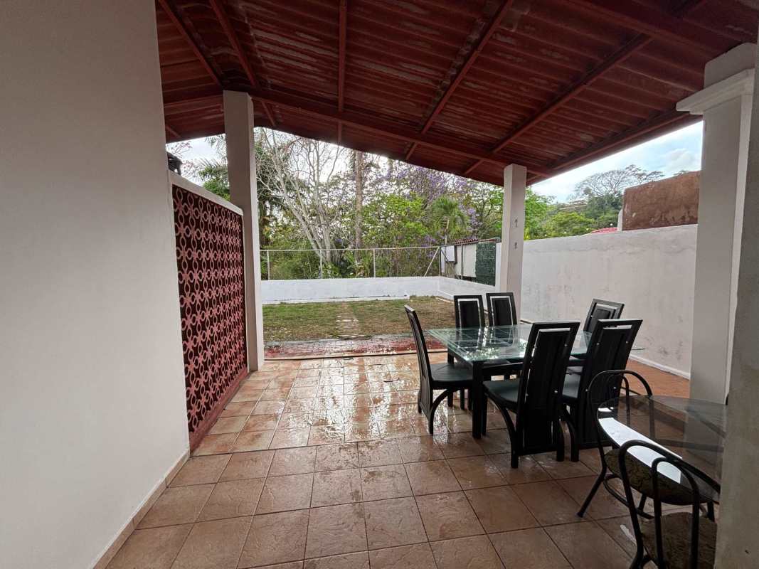 Bright outdoor covered terrace with dining area and privacy wall at the rental house in Brisas del Golf Panama
