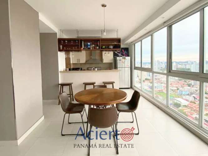 Dining area with round table, large skyline windows next to gourmet kitchen in Coco del Mar condo Panama City