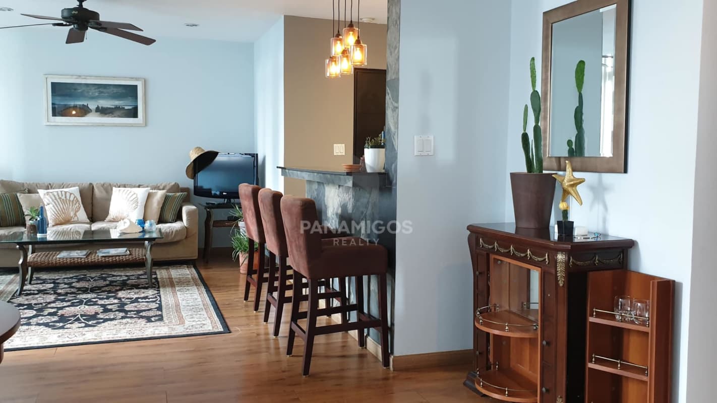 Living area with large sofa, breakfast bar, modern decor, panoramic windows PH Bayfront Panama City