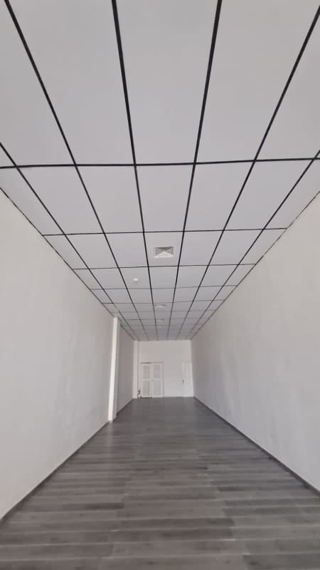 Empty interior space with grid ceiling, modern grey PVC flooring, recessed lights at Plaza El Dorado Panama