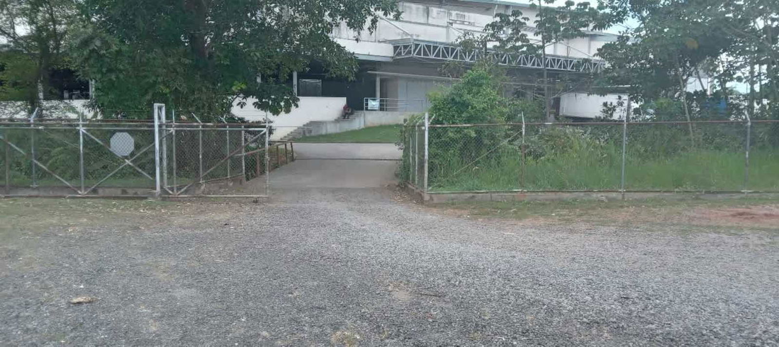 Secure chain-link fence gate with wide gravel drive at industrial storage property in Pedregal Panama