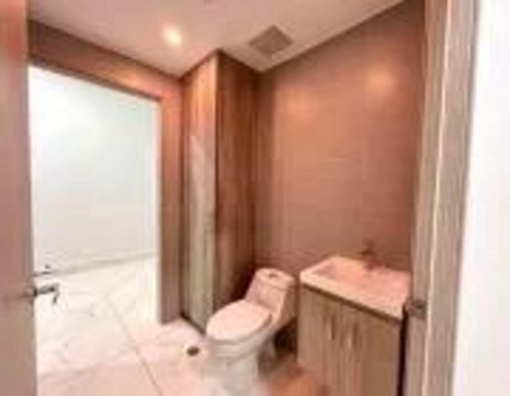 Modern bathroom with beige tile walls, toilet and sink inside medical office Panama