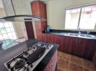 Kitchen featuring granite counters, gas cooktop, wood cabinets, window light Panama Pacifico