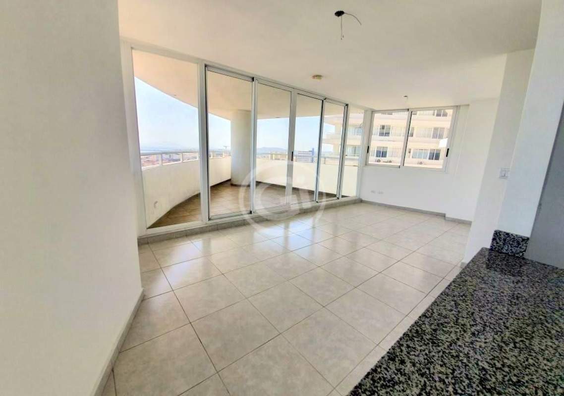 Modern living room with sliding glass doors opening to balcony overlooking Pacific Ocean and city skyline