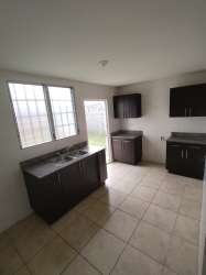 Contemporary tiled kitchen with cabinets and door to backyard in house for sale Panama