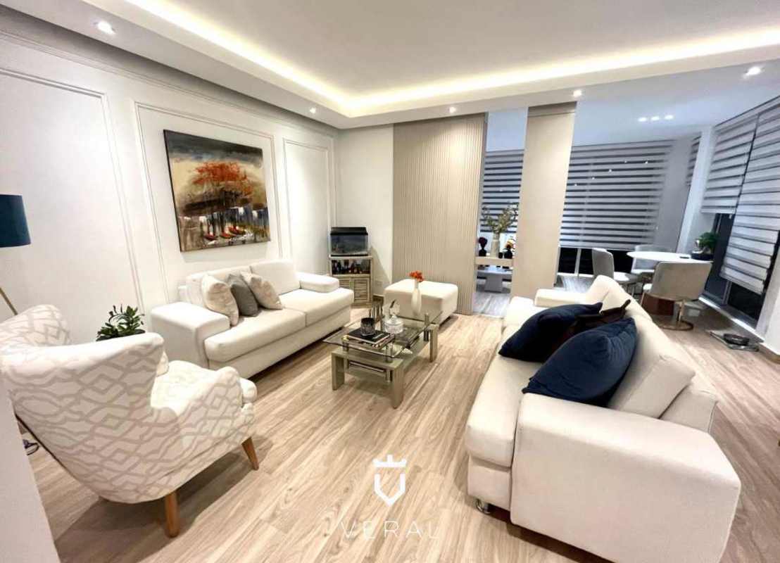 Living room furnished with sectional sofa, TV accent wall, striped blinds, in duplex rental house at Versalles Panama
