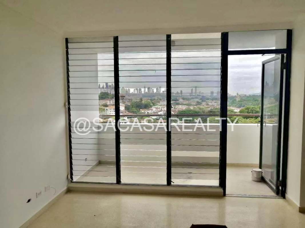 Spacious living room with balcony access overlooking city skyline PH Villa de las Fuentes Panama City