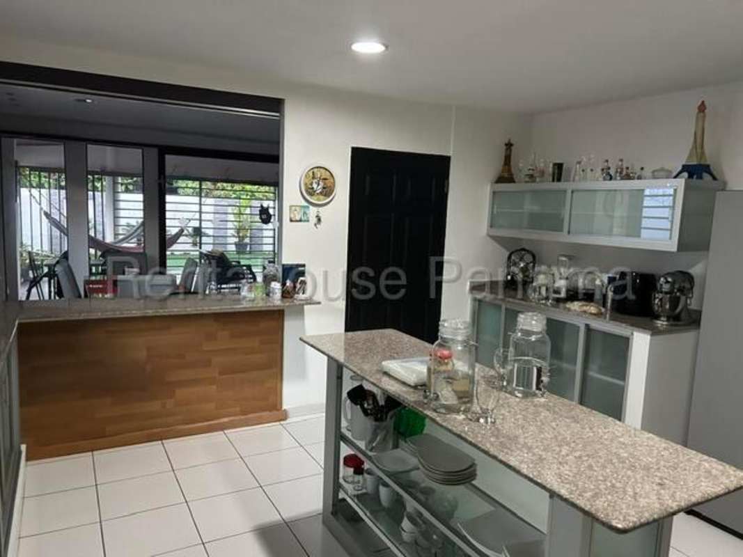 Landscaped backyard with garden area, mature trees, and seating in remodeled Chanis house Panama