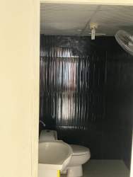 Small bathroom with black panel, white toilet and sink Villa Mercedes David Panama