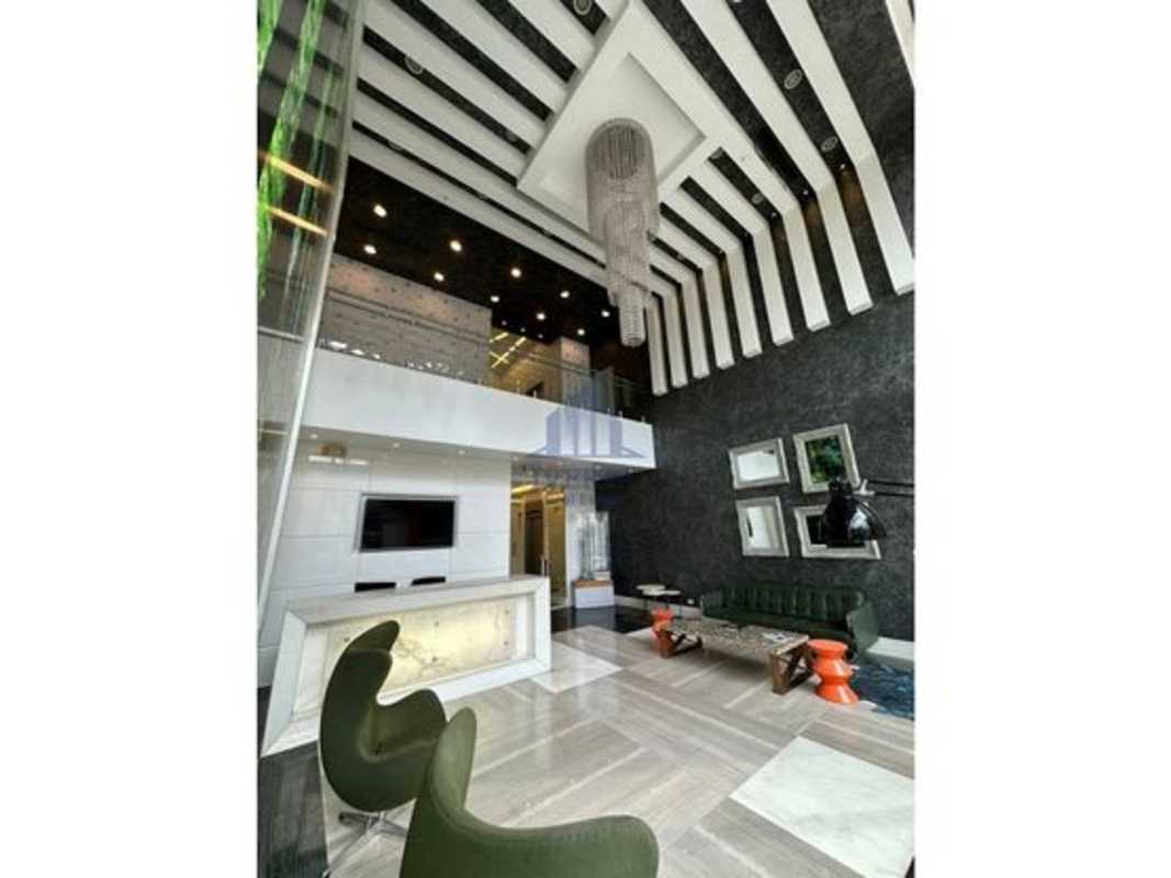 Double-height modern lobby with striped ceiling, chandelier, green lounge seating in PH BICSA Tower Panama City