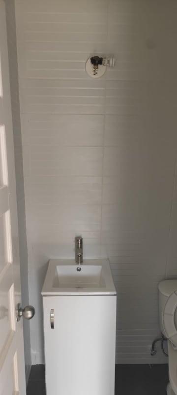 Minimalist bathroom with white textured walls, compact white vanity, chrome faucet in PH Vía Argentina El Cangrejo Panama apartment rent