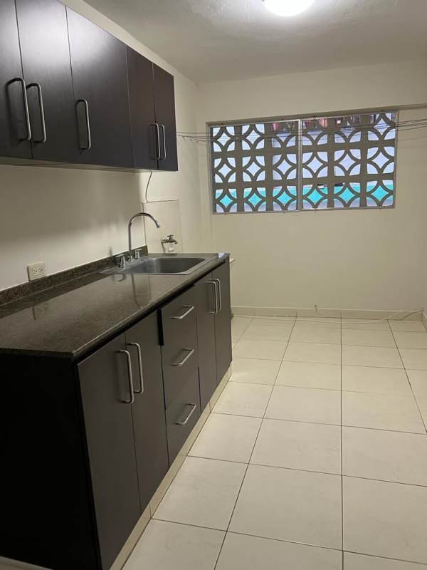 Kitchen with dark cabinets, tile floor, window with screen in apartment for rent Panama City
