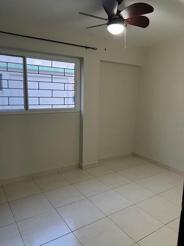 Bedroom with security bar window, ceiling fan, tiled floor in affordable apartment near Plaza Edison Panama