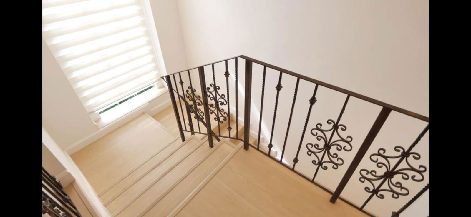 Wooden staircase with black iron railings large windows natural light in Albrook Gardens house