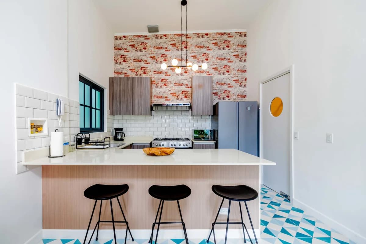Kitchen with marble island, white subway tile backsplash, brick accent wall, modern cabinetry Casco Viejo