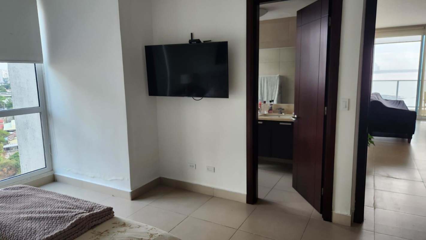 Modern bedroom with ensuite bathroom, large window city views, wall-mounted TV in PH Oceanaire Punta Pacífica