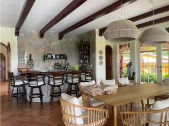 Dining room with rustic accents, stone wall, bar, wood beams in luxury estate San Carlos Panama