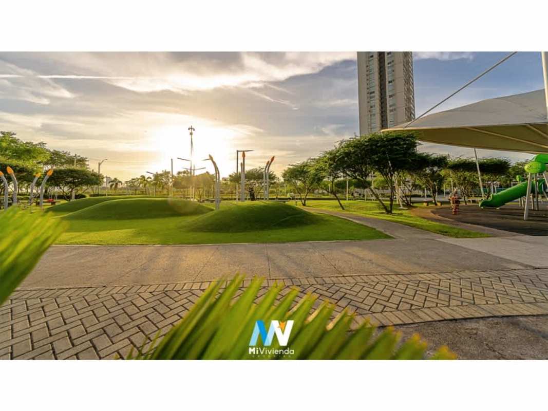 Modern landscaped park with playground, sidewalks, tall building Costa del Este