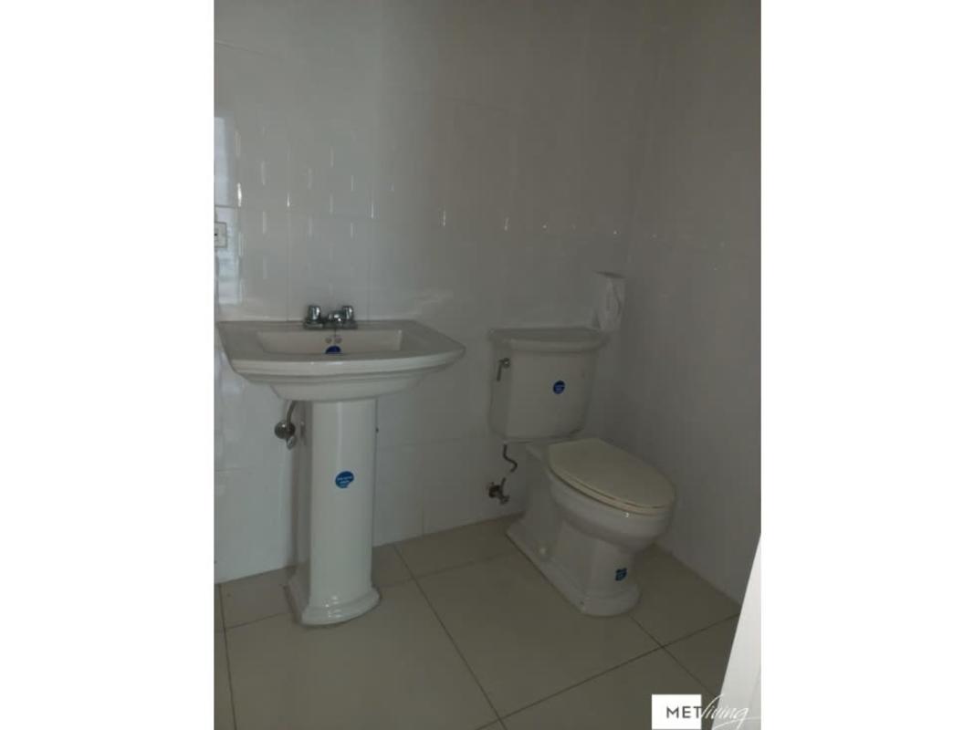 Minimalist bathroom with white pedestal sink, toilet, tiled walls and floor El Cangrejo office Panama City