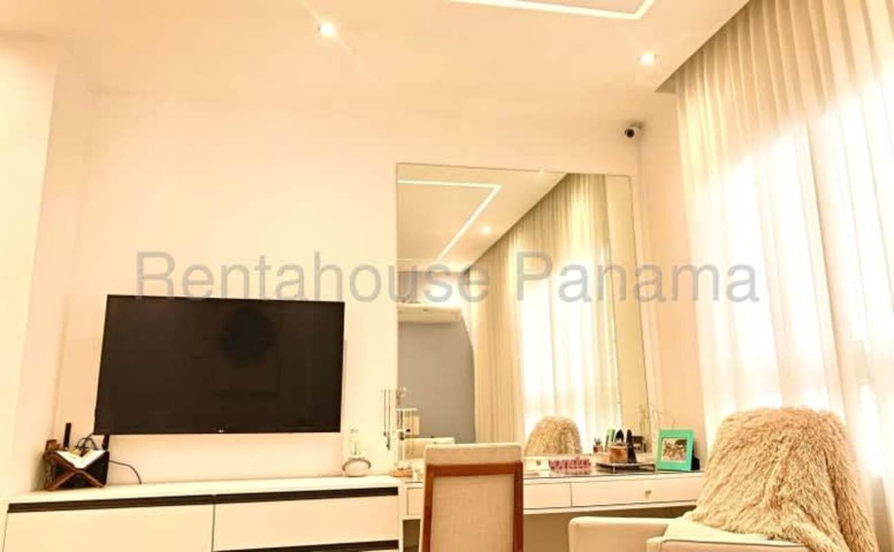Living room with wall TV, mirror, neutral palette in PH San Francisco Tower Panama City